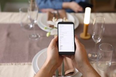 Photo of Couple choosing dishes from digital menu at restaurant, above view