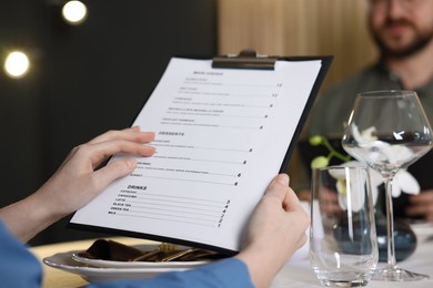 Photo of Couple choosing dishes from menu at table in restaurant, closeup