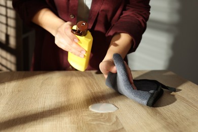 Photo of Woman polishing wooden table at home, closeup