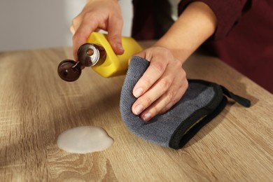 Photo of Woman polishing wooden table at home, closeup