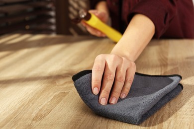 Photo of Woman polishing wooden table at home, closeup