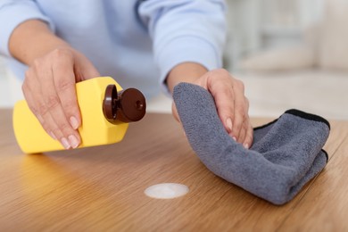 Photo of Woman polishing wooden table at home, closeup