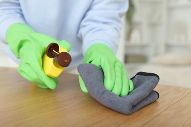 Photo of Woman polishing wooden table at home, closeup