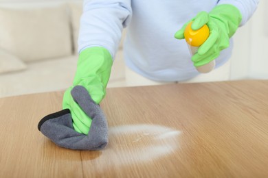 Photo of Woman polishing wooden table at home, closeup