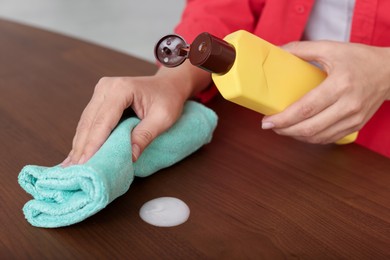 Photo of Woman polishing wooden table at home, closeup