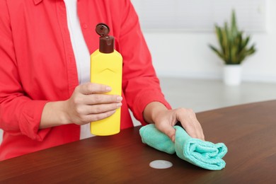 Photo of Woman polishing wooden table at home, closeup