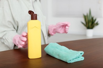 Photo of Woman polishing wooden table at home, closeup