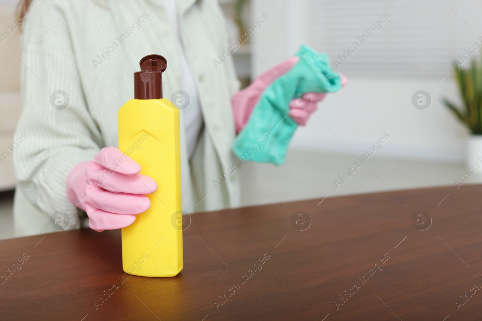 Photo of Woman polishing wooden table at home, closeup