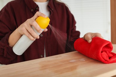 Photo of Woman polishing wooden table at home, closeup