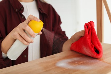 Photo of Woman polishing wooden table at home, closeup