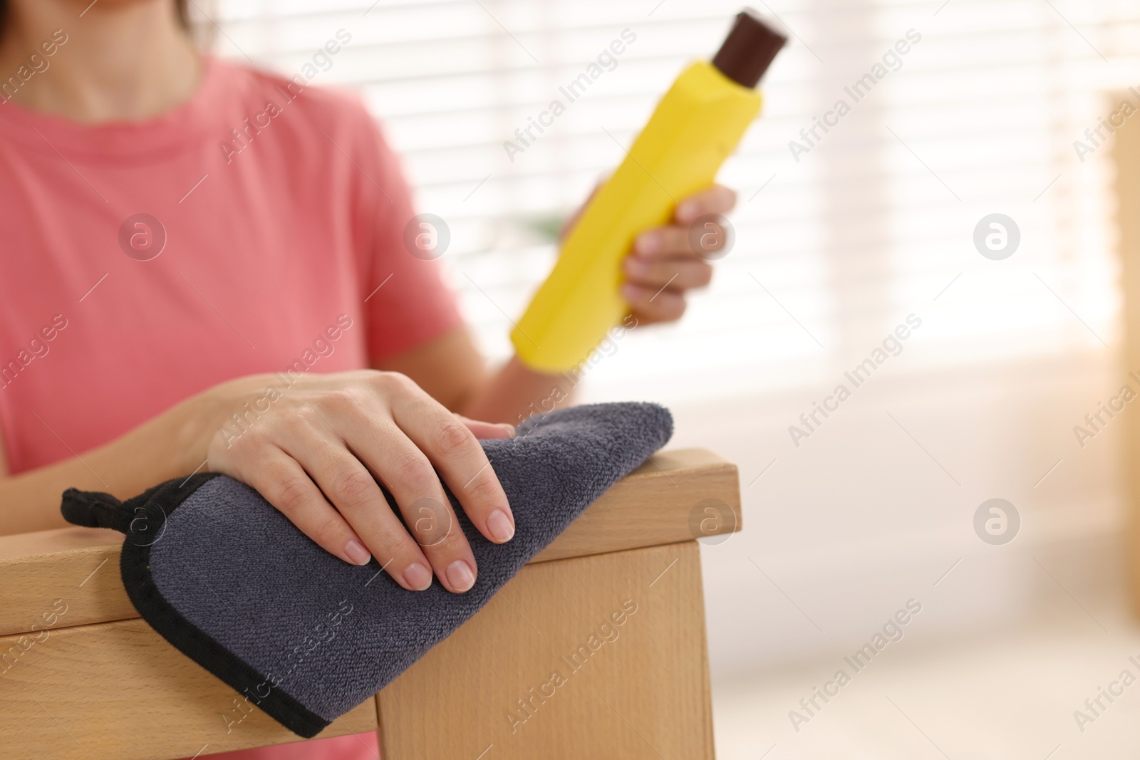 Photo of Woman with cleaning product and rag polishing wooden armrest at home, closeup. Space for text