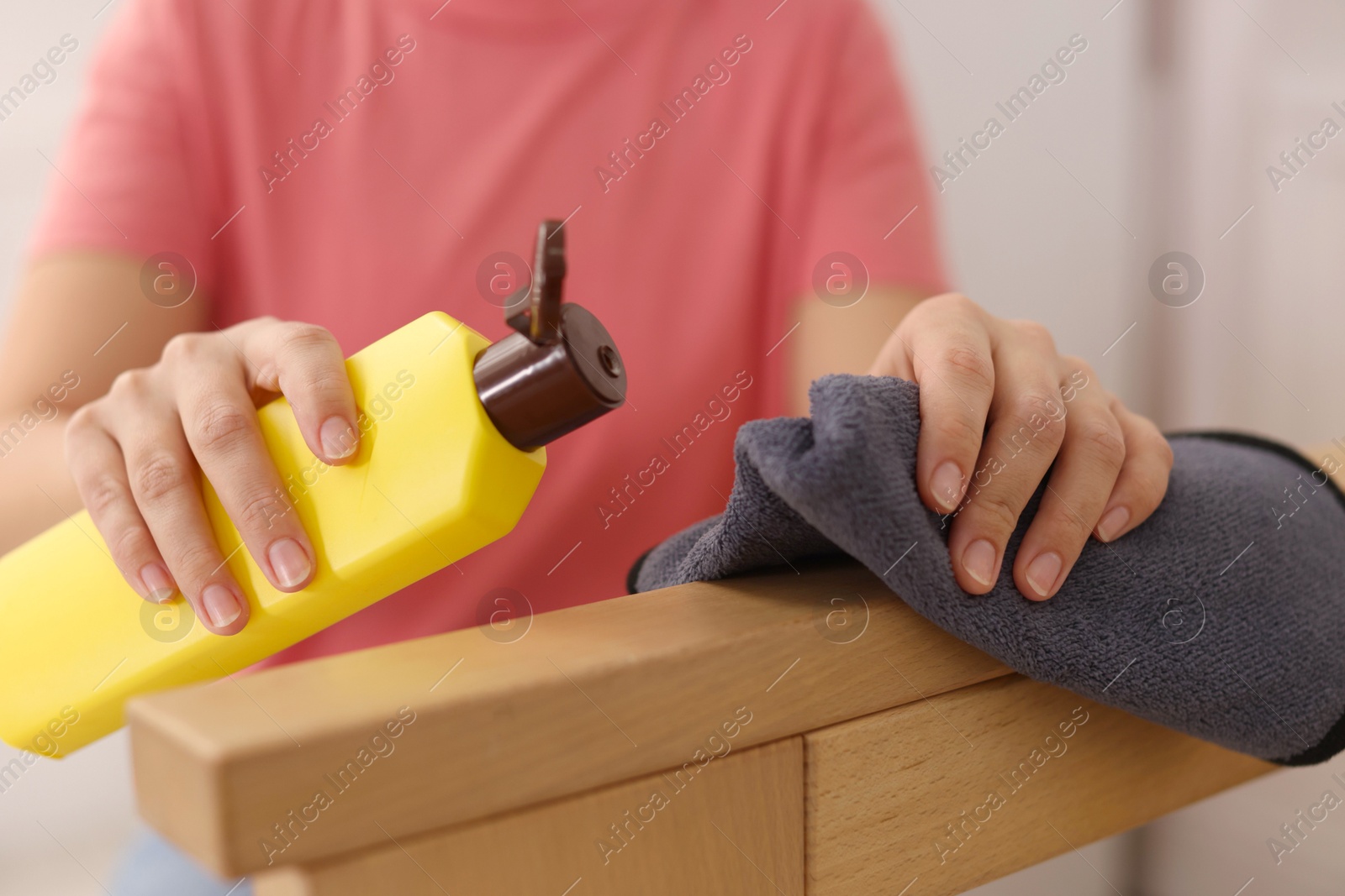 Woman with cleaning product and rag polishing wooden armrest at home, closeup Photo of Woman with cleaning product and rag polishing wooden armrest at home, closeup