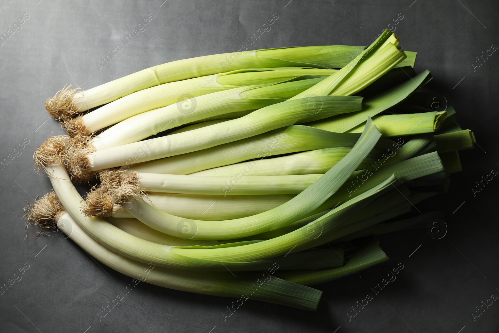 Photo of Fresh green leeks on grey table, top view