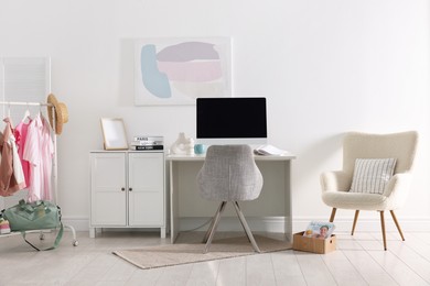 Photo of Home office. Comfortable workplace near white wall. Desk with computer and other furniture in room