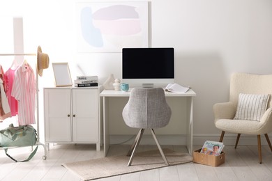 Photo of Home office. Comfortable workplace near white wall. Desk with computer and other furniture in room