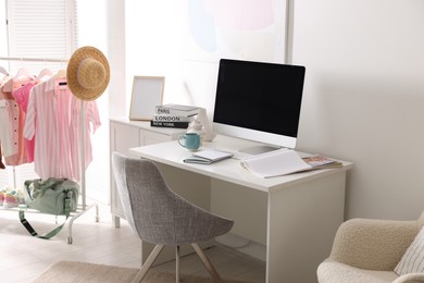 Home office. Comfortable workplace near white wall. Desk with computer and other furniture in room