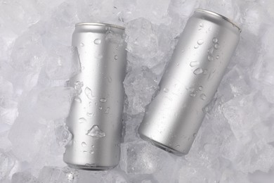 Photo of Refreshing drinks in cans on ice cubes, top view