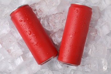Photo of Refreshing drinks in cans on ice cubes, top view