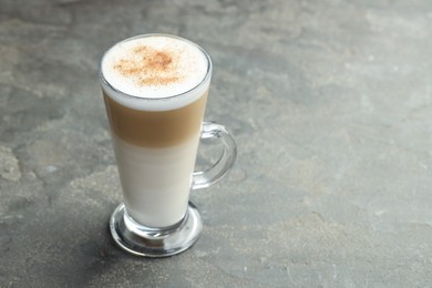 Photo of Tasty latte macchiato in glass cup on grey table, closeup. Space for text