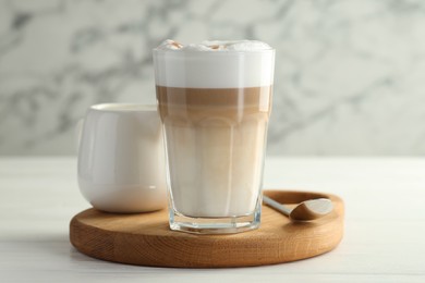 Photo of Tasty latte macchiato in glass on white wooden table, closeup