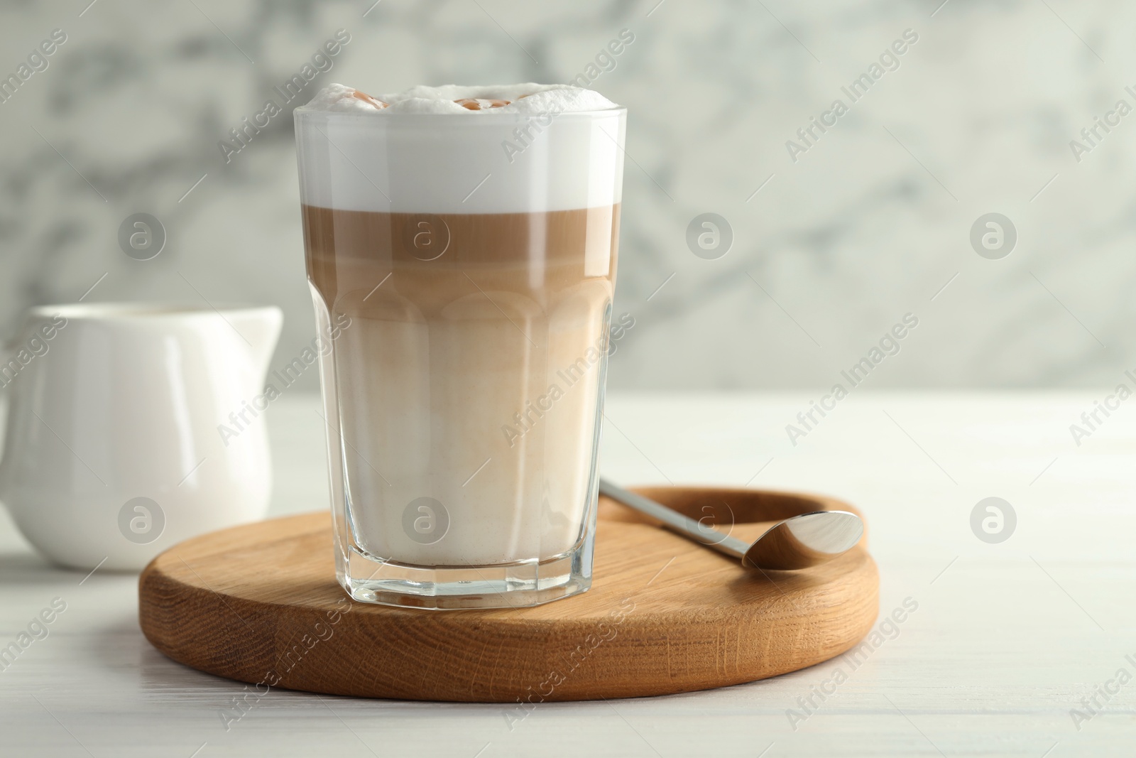 Photo of Tasty latte macchiato in glass on white wooden table, closeup