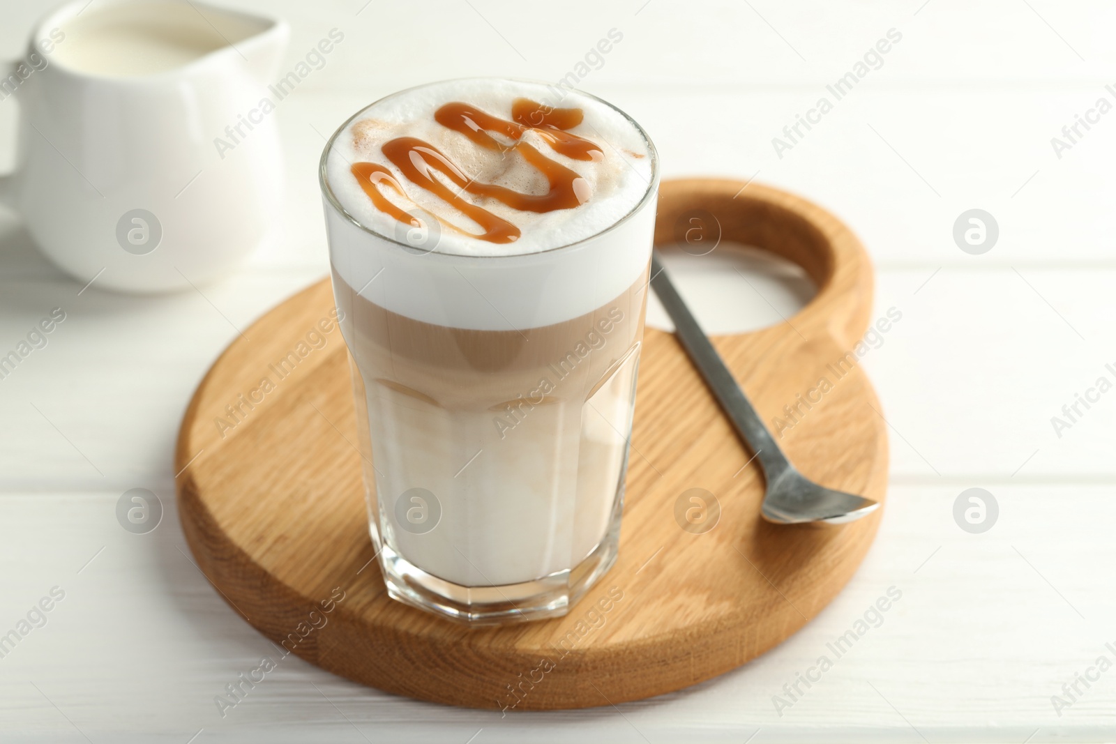 Photo of Tasty latte macchiato in glass on white wooden table, closeup