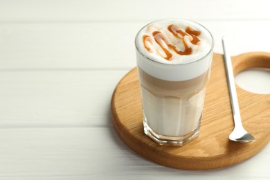 Photo of Tasty latte macchiato in glass on white wooden table, closeup. Space for text