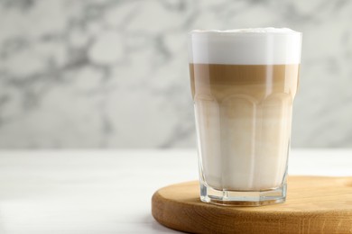 Photo of Tasty latte macchiato in glass on white wooden table, closeup. Space for text