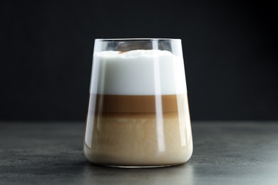 Photo of Tasty latte macchiato in glass on grey table, closeup