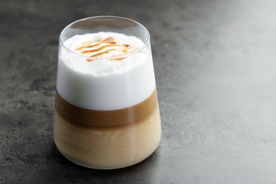 Photo of Tasty latte macchiato in glass on grey table, closeup. Space for text