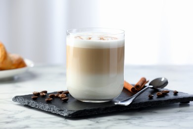 Photo of Tasty latte macchiato in glass on marble table, closeup. Coffee drink