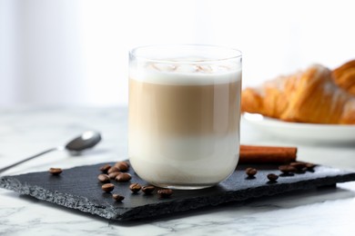 Photo of Tasty latte macchiato in glass on marble table, closeup. Coffee drink