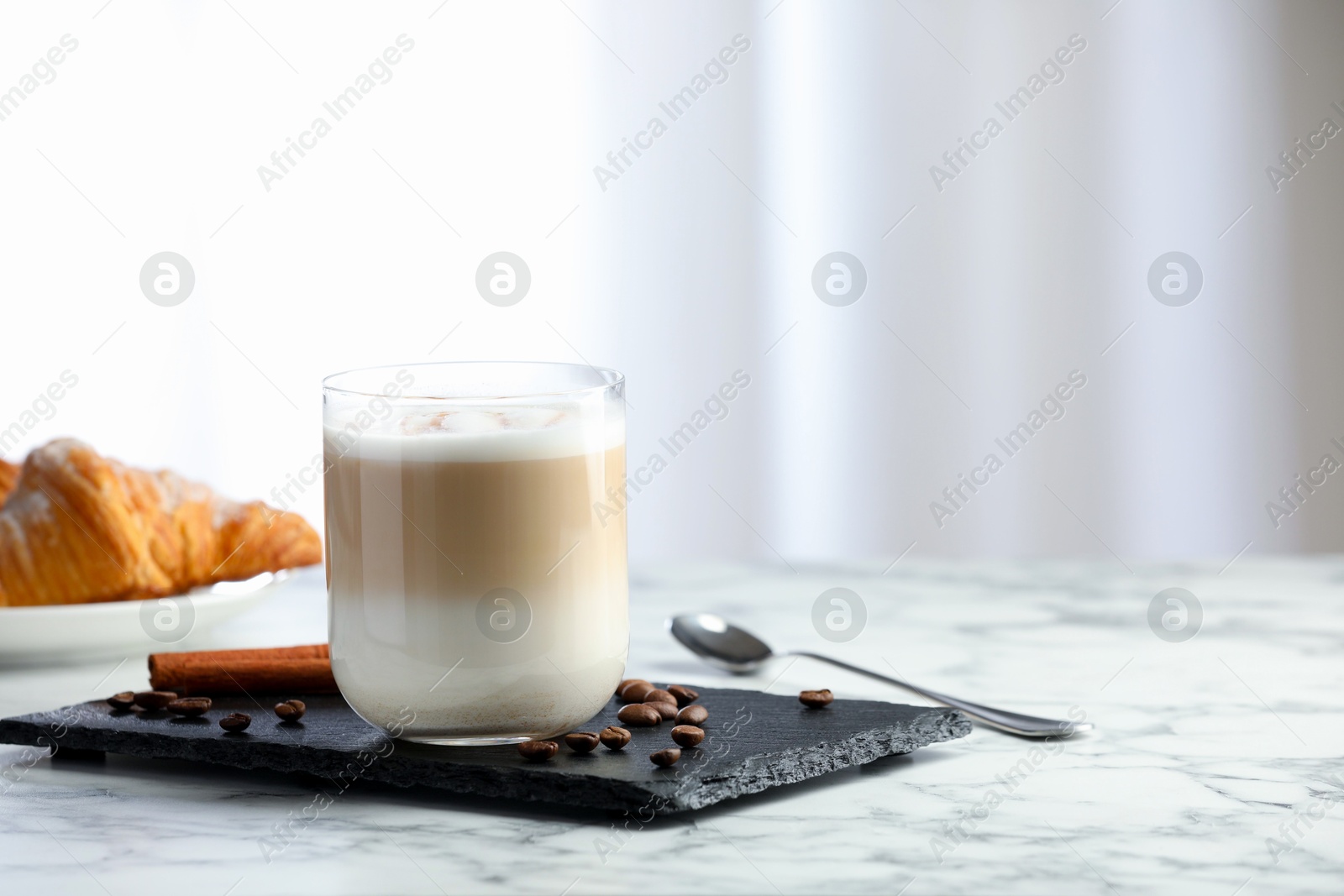 Photo of Tasty latte macchiato in glass on marble table, space for text. Coffee drink