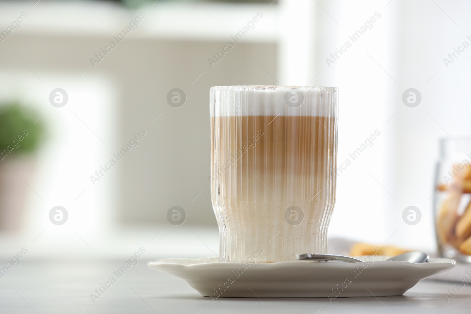 Photo of Tasty latte macchiato in glass on white table, closeup. Coffee drink