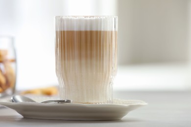 Photo of Tasty latte macchiato in glass on white table, closeup. Coffee drink