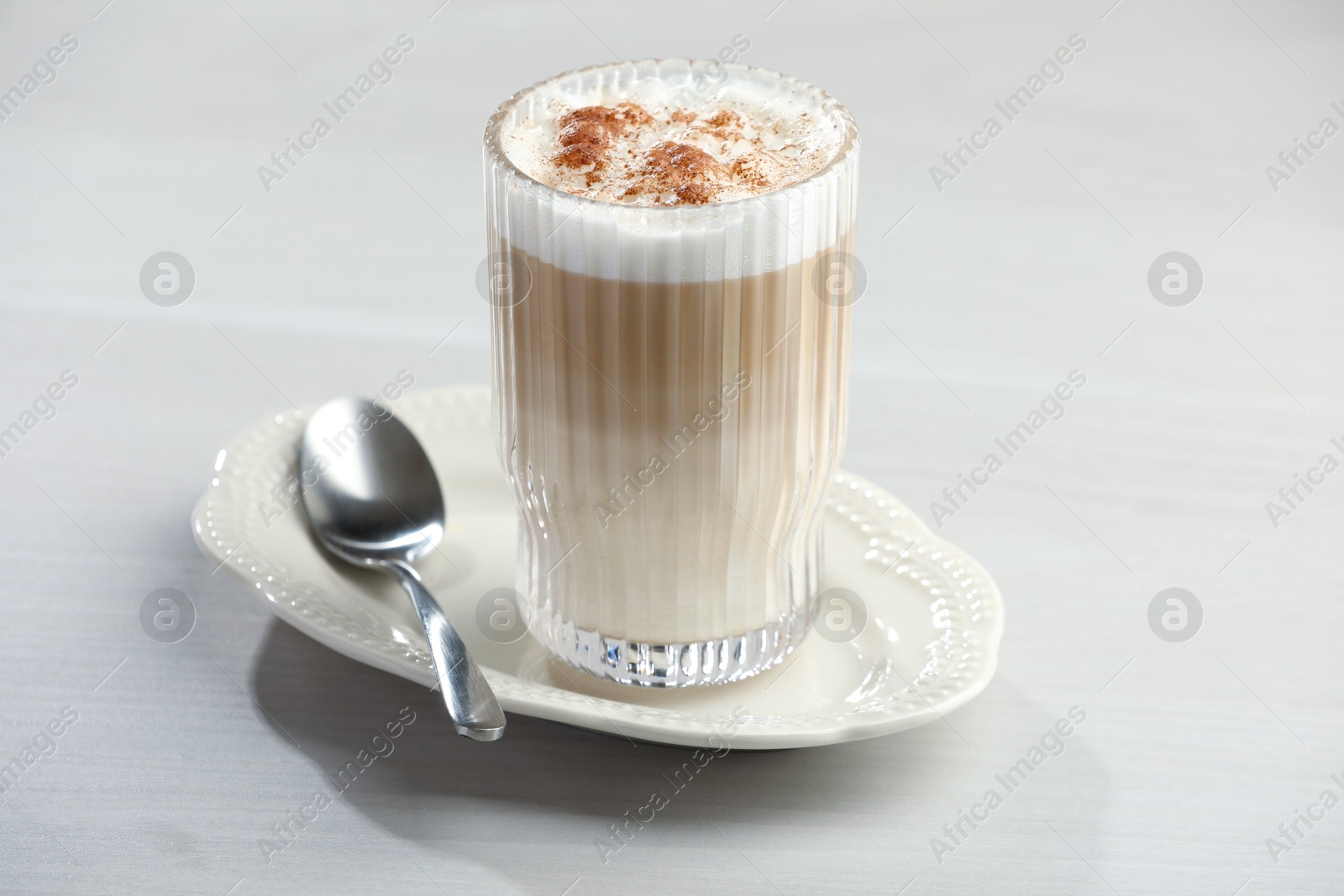 Photo of Tasty latte macchiato in glass on white table, closeup. Coffee drink