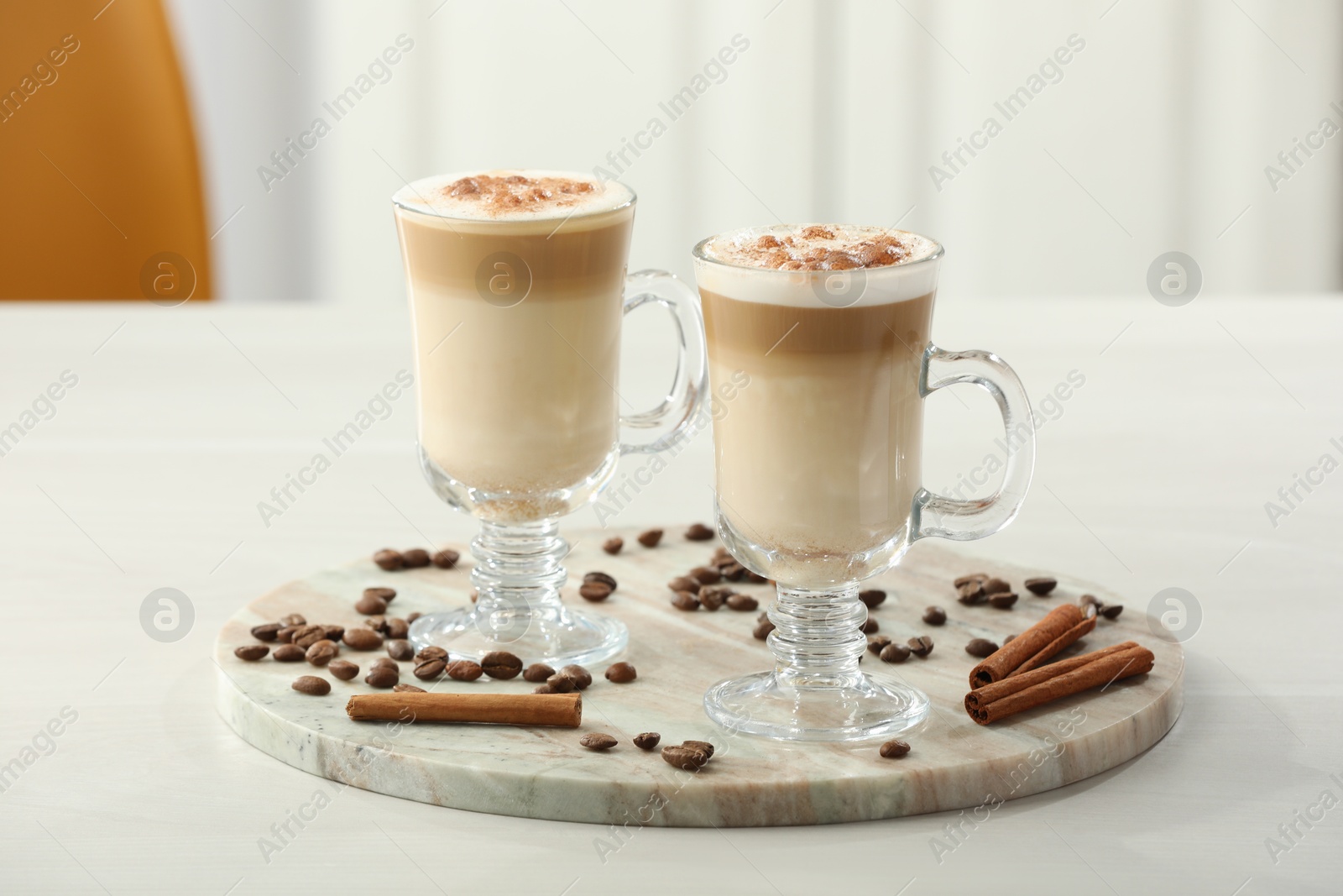 Photo of Tasty latte macchiato, coffee beans and cinnamon sticks on white table