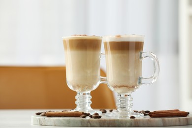 Photo of Tasty latte macchiato, coffee beans and cinnamon sticks on white table, closeup