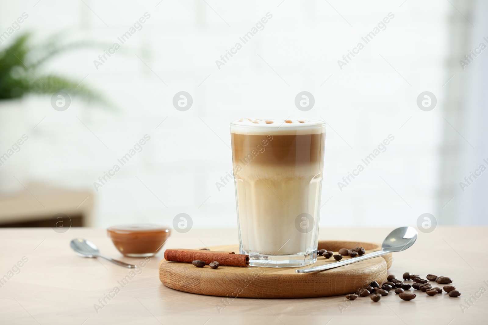 Photo of Tasty latte macchiato in glass on wooden table