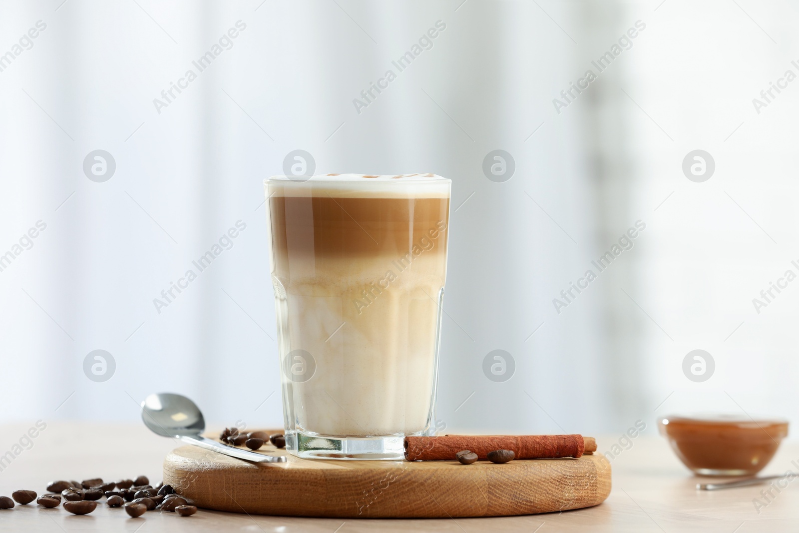 Photo of Tasty latte macchiato in glass on wooden table, space for text