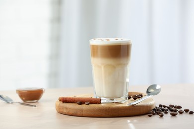 Photo of Tasty latte macchiato in glass on wooden table, space for text