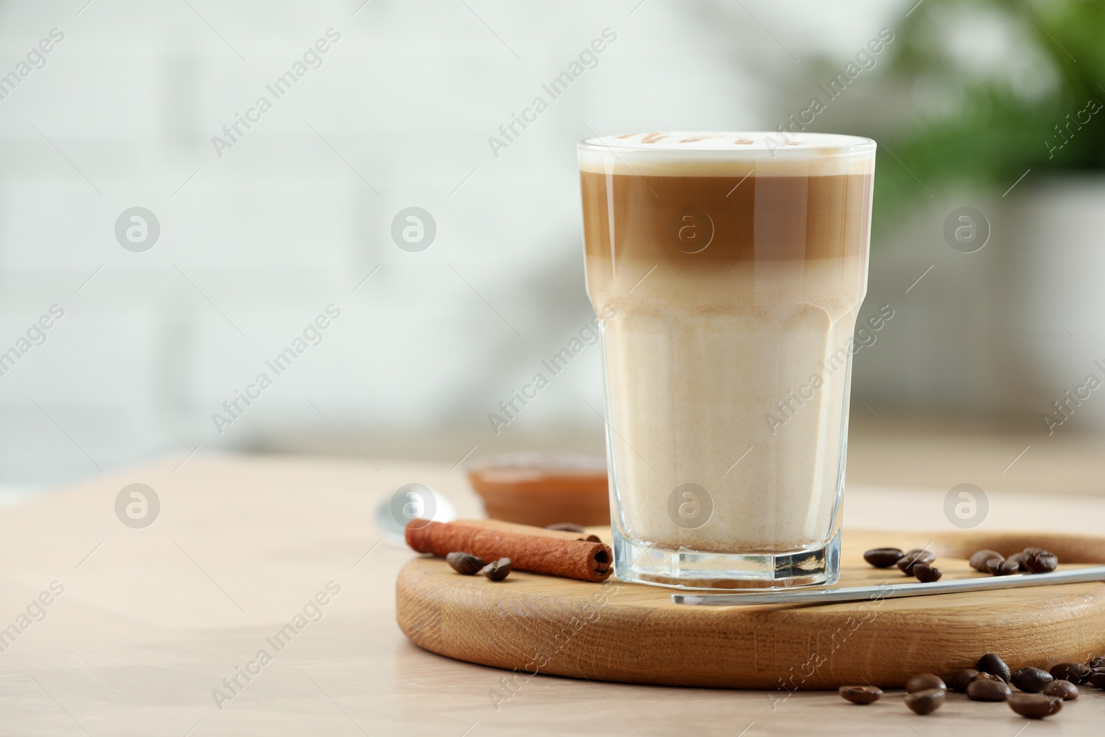 Photo of Tasty latte macchiato in glass on wooden table, closeup. Space for text