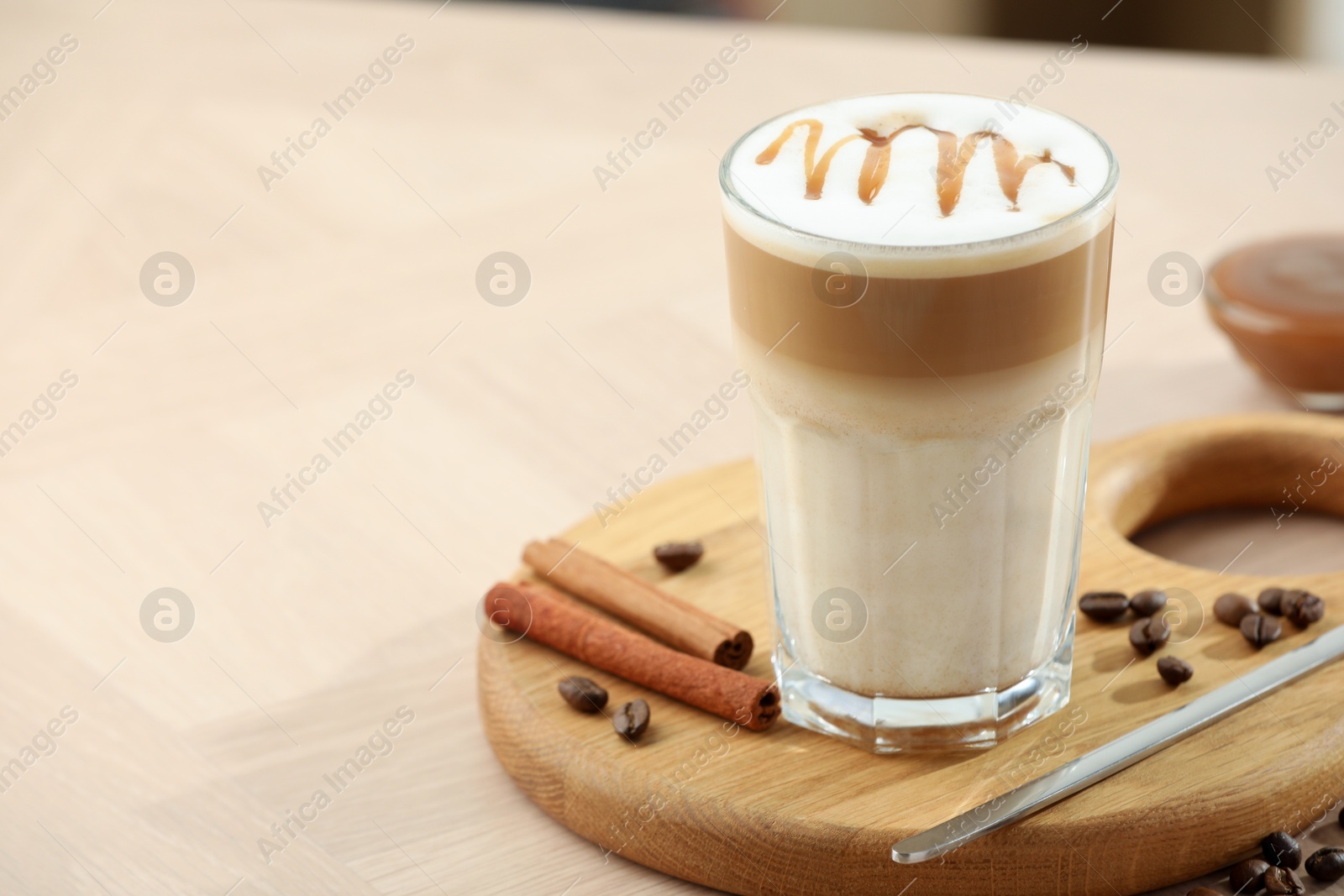 Photo of Tasty latte macchiato in glass on wooden table, closeup. Space for text