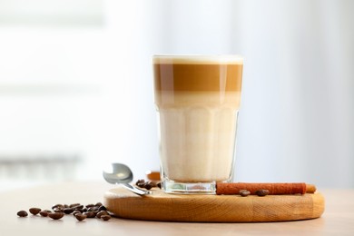 Photo of Tasty latte macchiato in glass on wooden table, closeup