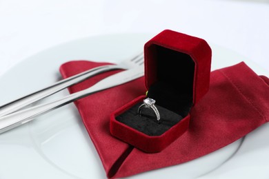 Beautiful engagement ring and setting for romantic dinner on white background, closeup