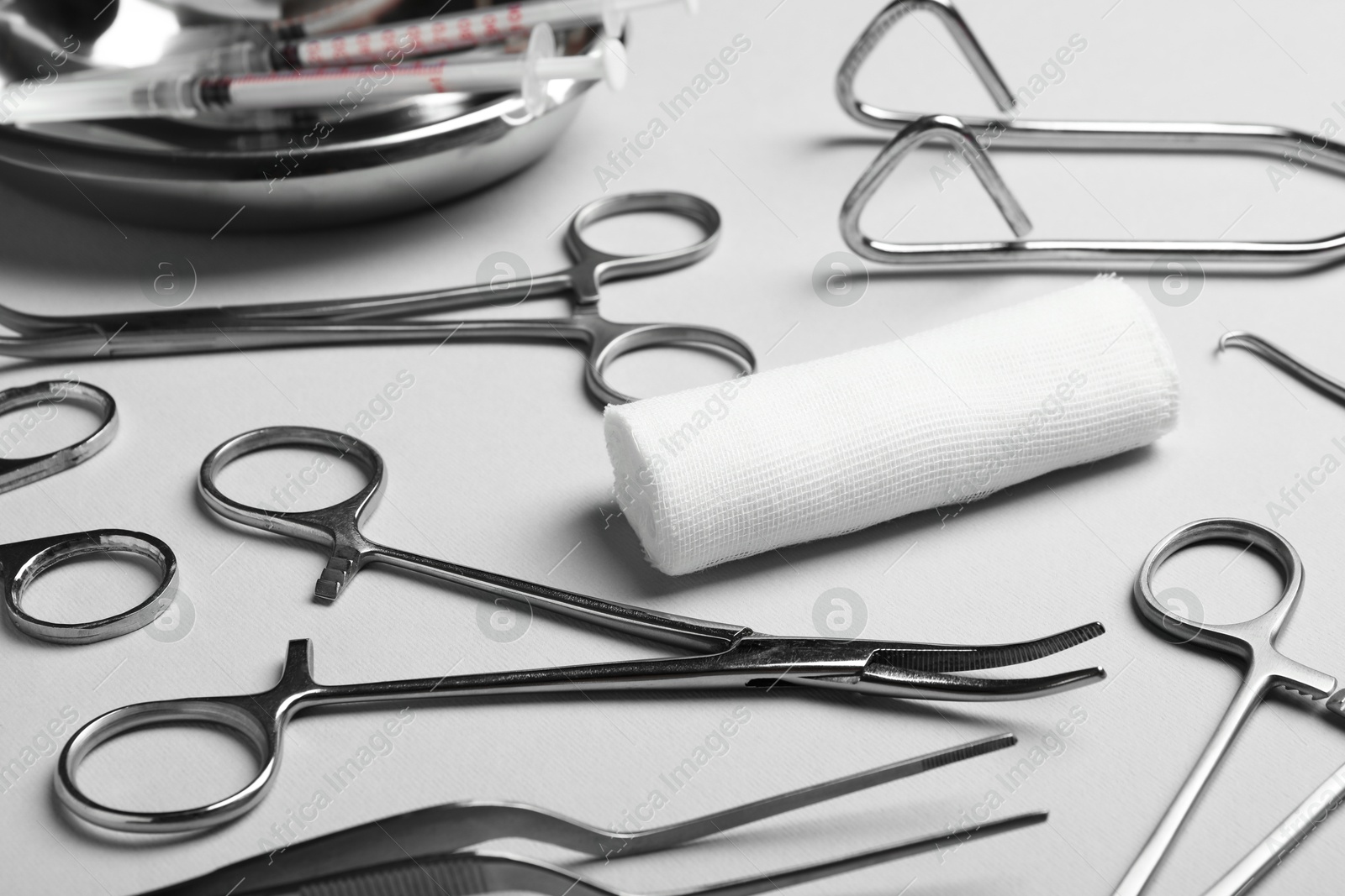 Photo of Different surgical instruments on light grey background, closeup