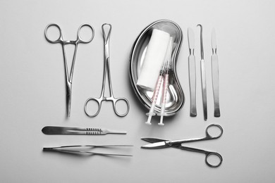 Photo of Different surgical instruments on light grey background, flat lay