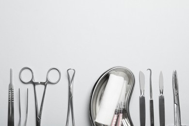 Different surgical instruments on light grey background, flat lay. Space for text