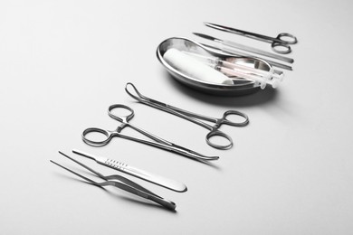 Photo of Different surgical instruments on light grey background, closeup