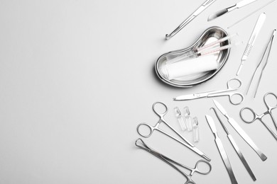 Different surgical instruments on light grey background, flat lay. Space for text